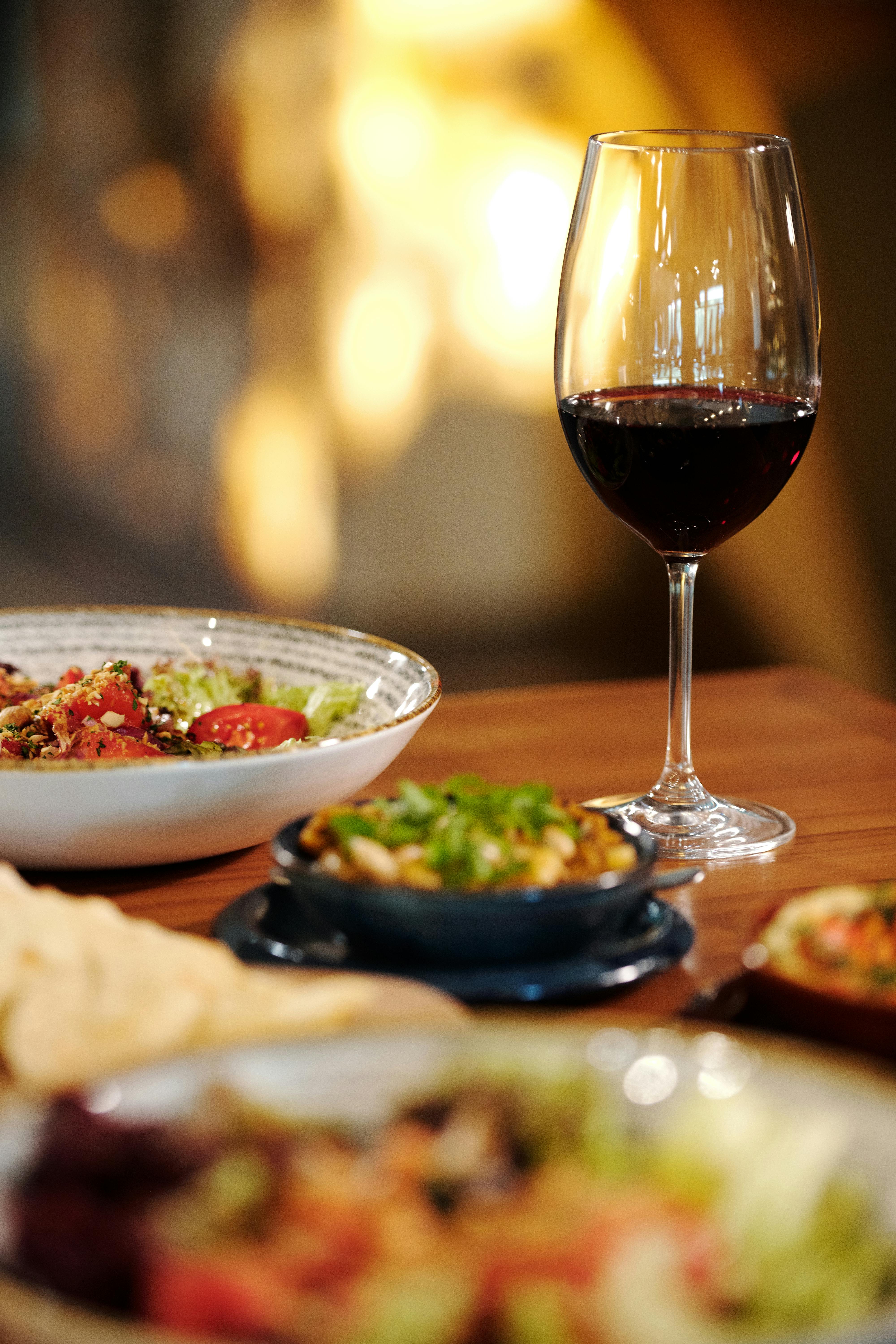 A glass of red wine paired with gourmet dishes in a cozy restaurant setting, perfect for a romantic dinner.